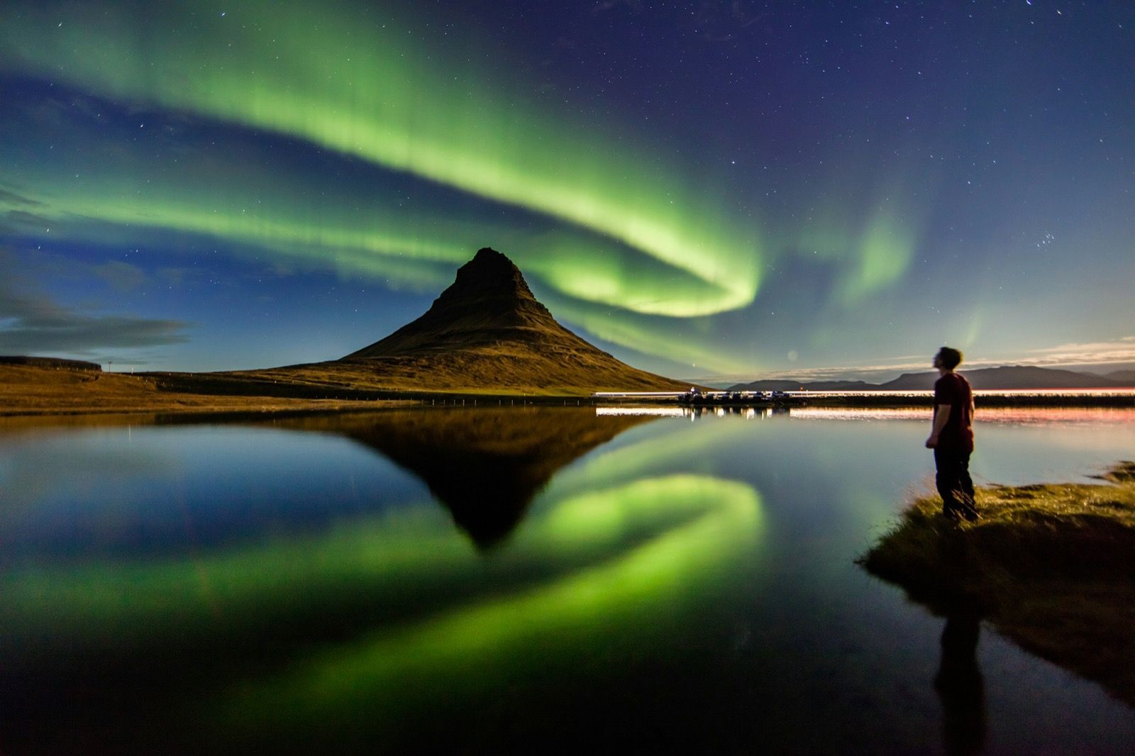 Aurora boreal sobre la montaña Kirkjufell reflejada en el agua, Islandia